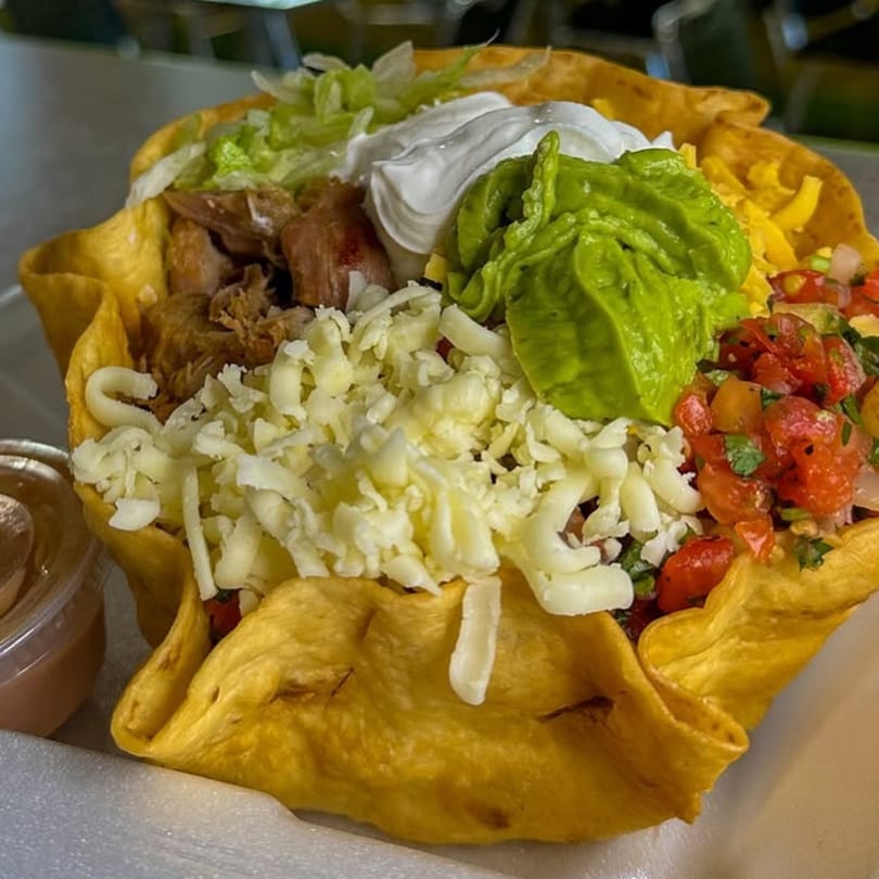 A Flying Burro taco salad in a crispy tortilla bowl, filled with meat, cheese, guacamole, and salsa.