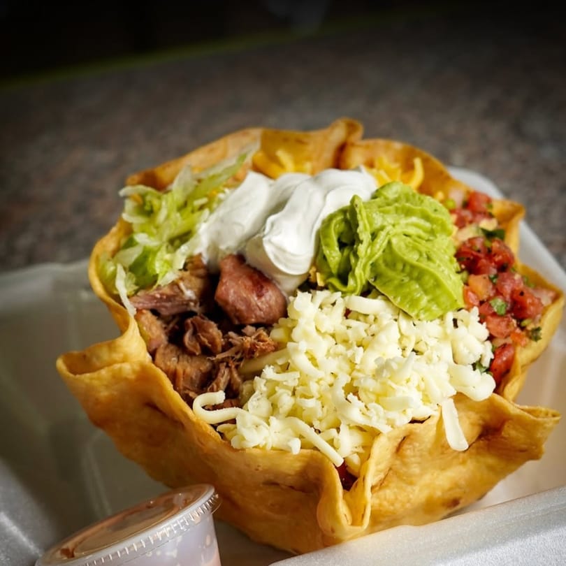 A Flying Burro taco salad in a crispy tortilla bowl, filled with meat, cheese, guacamole, and salsa.
